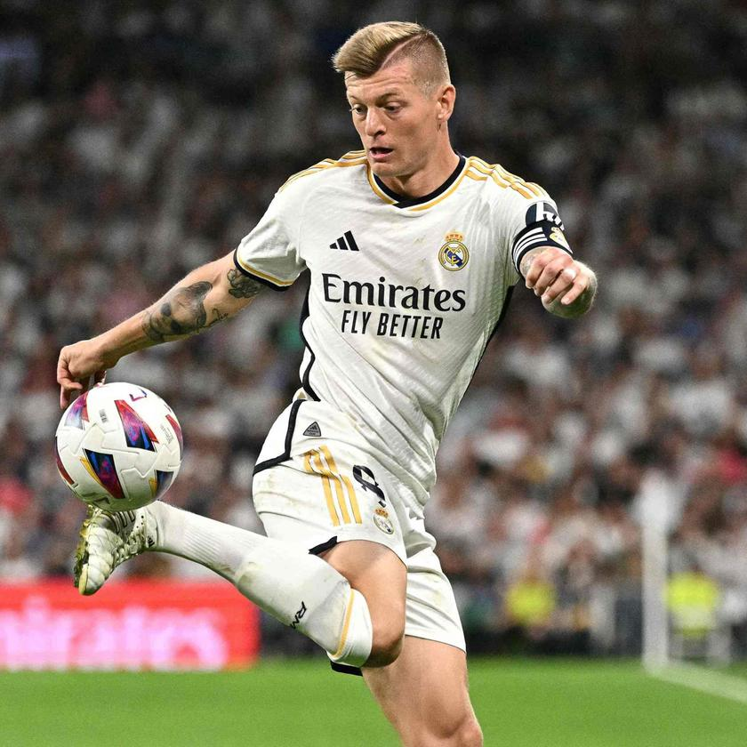 Toni Kroos - pomocnik - w białym stroju Realu Madryt kontroluje piłkę w powietrzu podczas meczu na stadionie pełnym kibiców.